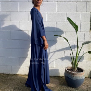 May include: A long, navy blue maxi dress with a V-neckline and flowing sleeves. The dress has a side slit and is made of a soft, lightweight fabric.