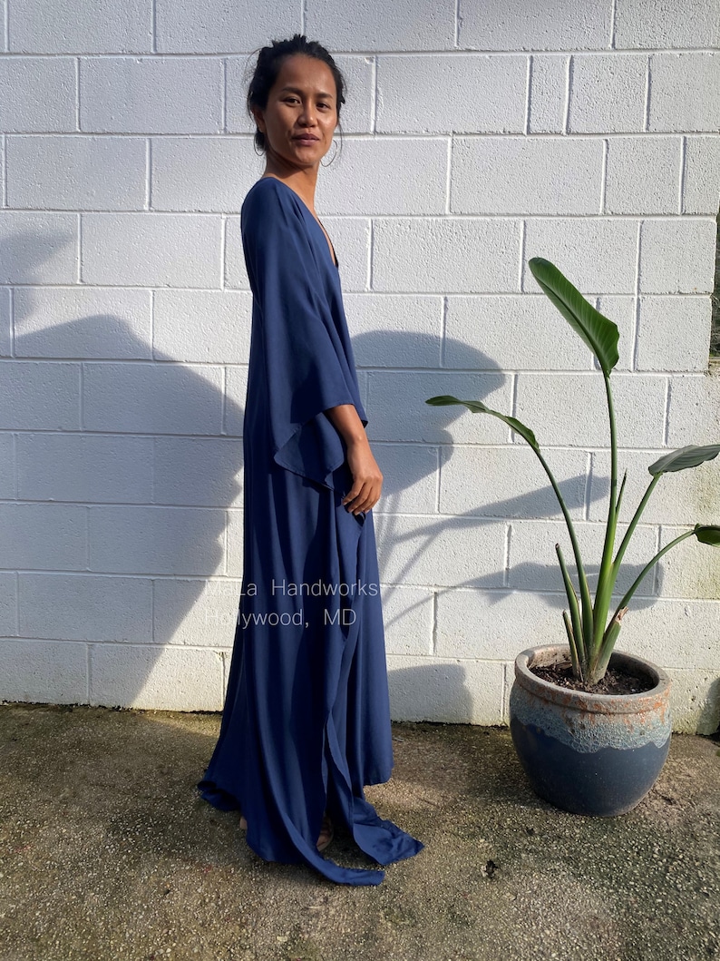 May include: A long, navy blue maxi dress with a V-neckline and flowing sleeves. The dress has a side slit and is made of a soft, lightweight fabric.