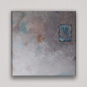 May include: Square abstract painting with a textured surface. The artwork features a muted color palette of grays, blues, and hints of pink and orange. A rectangular shape in shades of blue is in the upper right corner.