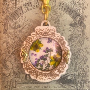 Ce mini porte-clés circulaire en forme de fleur dans un cadre vintage tient dans votre poche ou se fixe à votre sac ou à votre porte-clés. Super cadeau pour la fête des mères.