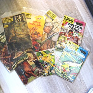 May include: A collection of vintage paperback books with colorful covers featuring illustrations and titles like "Uncle Tom's Cabin", "Under Two Flags", "Oregon Trail", and "Twenty Thousand Leagues Under the Sea".