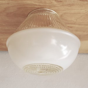 May include: A flush mount ceiling light fixture featuring a clear, vertically ribbed glass top section that transitions into a smooth, opaque white glass bowl, finished with a circular, textured clear glass detail at the very bottom center.
