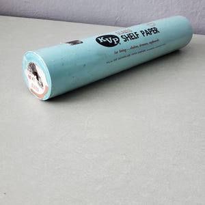 May include: A roll of light blue KVP shelf paper for lining shelves, drawers, and cupboards. The label reads "GLAZED" and "10 FT". The KVP logo is visible on the roll. The paper is rolled up and ready to use.