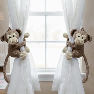 "Handmade crochet brown monkey curtain tie-back for a nursery, featuring a cute knitted monkey with long arms wrapped around a curtain. Ideal for jungle-themed kids' room decor and baby shower gifts.