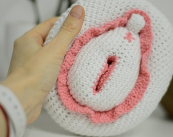 May include: A crocheted anatomical heart with a pink and white color scheme. The heart is made of yarn and has a textured surface.