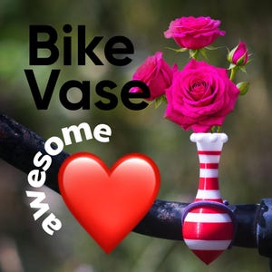 Könnte beinhalten: Ein Fahrradvase mit rot-weißem Streifendesign, die leuchtend rosa Rosen hält. Das Bild enthält die Worte "Bike Vase awesome" und ein rotes Herz-Emoji. Die Vase ist an einem schwarzen Fahrradlenker befestigt.
