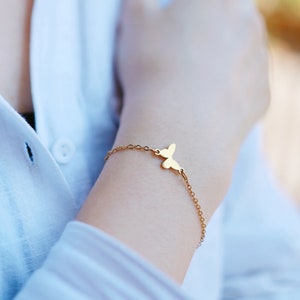 May include: A delicate gold chain bracelet with a small butterfly charm.