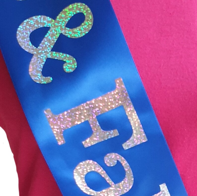 May include: A blue satin sash with the words "& Forever" in silver glitter lettering.