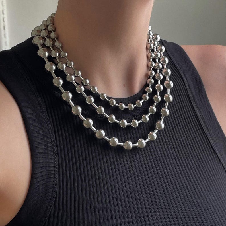 Peut inclure: Un collier en cha&icirc;ne argent avec trois rangs de gros perles rondes.