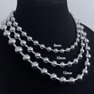Peut inclure: Trois colliers en cha&icirc;ne &agrave; billes argent&eacute;es avec des perles de diff&eacute;rentes tailles. La plus petite cha&icirc;ne a des perles de 8 mm, la cha&icirc;ne du milieu a des perles de 10 mm et la plus grande cha&icirc;ne a des perles de 12 mm.