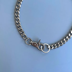 Puede incluir: Un collar de cadena de plata con un dise&ntilde;o de eslabones curb y un cierre de langosta de plata.
