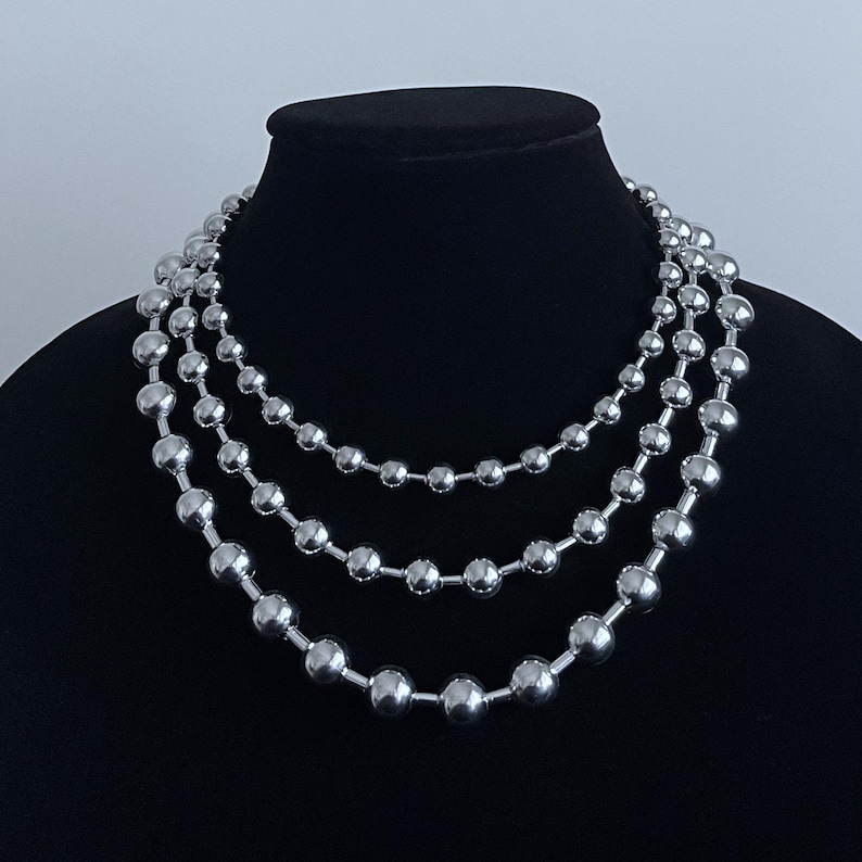 Peut inclure: Un collier argent&eacute; avec trois rangs de grosses perles rondes.