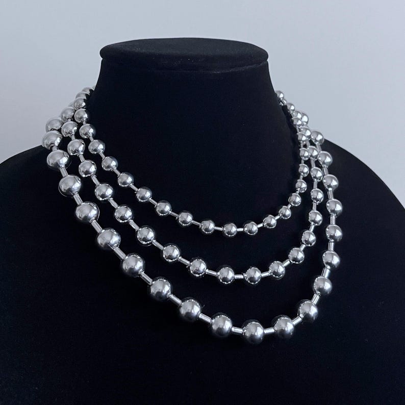 Peut inclure: Un collier argent&eacute; compos&eacute; de trois rangs de grosses perles rondes.