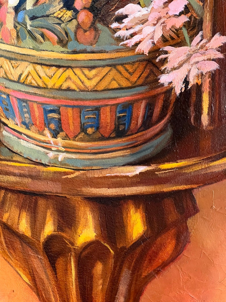 May include: A decorative ceramic pot with a geometric pattern in shades of yellow, blue, red, and brown. The pot is filled with pink flowers and sits on a wooden stand with a gold finish.