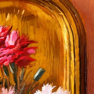 May include: A close-up of a painting of pink and red flowers in a gold frame. The flowers are painted in a realistic style and the frame is ornate.