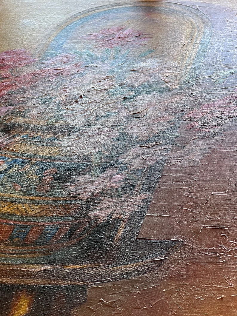 May include: A close-up of a painting depicting a vase with pink flowers. The vase is decorated with a geometric pattern in shades of blue, yellow, and brown. The background is a muted brown.