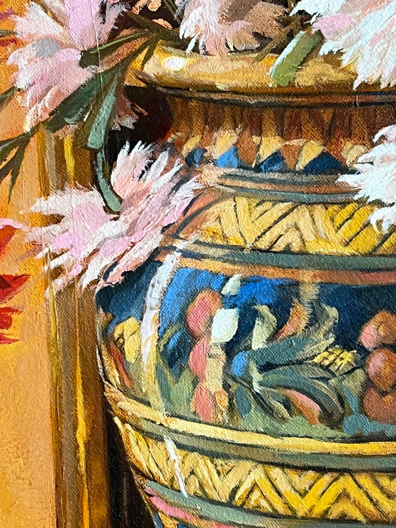May include: A close-up of a pink and white flower arrangement in a large, ornate, yellow and blue ceramic vase. The vase has a geometric pattern and is decorated with a floral motif.