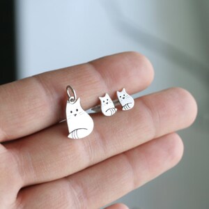 Puede incluir: Un conjunto de pendientes de plata con forma de gato y un collar con un colgante de plata con forma de gato. Los dijes con forma de gato son simples y minimalistas, con un dise&ntilde;o lindo de estilo de dibujos animados.