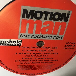 May include: A red vinyl record with a white label. The label has black text that reads "MOTION man feat Kut Masta Kurt" and "threshold recordings". The track list includes "Loose Cannon (Vocal)", "Trounce (Vocal)", and "We Work Styles (Vocal)".