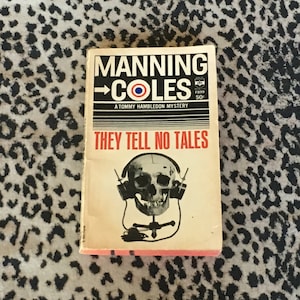 May include: A paperback book cover with a black and white illustration of a skull wearing headphones. The book title is "They Tell No Tales" and the author is Manning Coles. The book is a Tommy Hambledon mystery.
