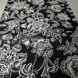 Peut inclure: Tissu noir et blanc avec un motif floral. Le tissu présente un motif répétitif de grandes et petites fleurs avec des détails complexes.