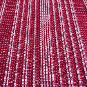May include: Close-up of a woven textile with a repeating pattern of vertical stripes. The stripes alternate between a deep red and white. The texture appears to be slightly raised, creating a subtle visual depth.