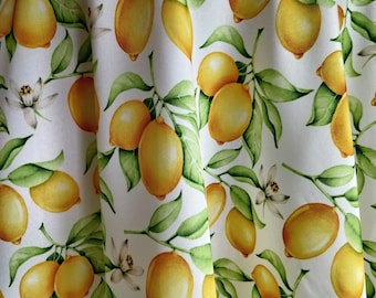 May include: White fabric with a repeating pattern of yellow lemons and green leaves. The lemons are drawn in a realistic style with subtle shading.