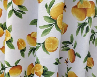 May include: White fabric with a repeating pattern of yellow lemons and green leaves. The lemons are in various sizes and shapes, and some have a slice cut out of them. There are also small yellow bees scattered throughout the pattern.
