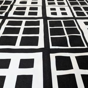Peut inclure: Une courtepointe présentant un motif géométrique répétitif de cadres blancs semblables à des fenêtres sur un fond noir uni. Le design se compose de blocs rectangulaires divisés en sections plus petites par des lignes blanches, créant un aspect quadrillé.