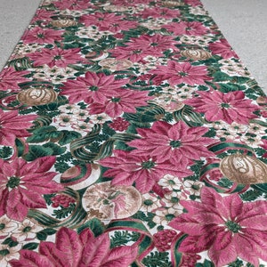 May include: A rectangular table runner with a festive floral pattern. The runner features large, deep pink poinsettias, white flowers, and green foliage on a white background. Decorative elements include brown ornaments and green ribbons.