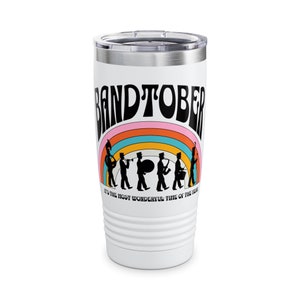May include: White stainless steel tumbler with a black and white graphic of a marching band with a rainbow behind them. The text "Bandtober" is in a retro font above the band. The text "It's the most wonderful time of the year" is below the band.