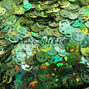 Op de afbeelding: Een close-up afbeelding van een grote stapel groene, iriserende glitter in de vorm van smiley's.