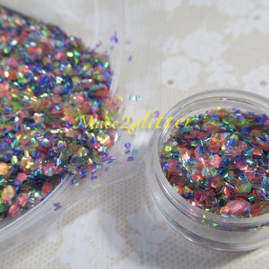 May include: A close-up of iridescent glitter in a clear plastic bag and a small clear jar. The glitter is a mix of pink, blue, green, and gold.