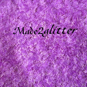 May include: A close-up image of a bowl filled with purple glitter. The glitter is made of small, thin pieces of plastic that have a metallic sheen. The glitter is perfect for adding sparkle to crafts, decorations, and more. The text "Made2glitter" is visible in the image.
