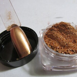 May include: A small jar of copper glitter with a clear lid. A clear plastic stick with a copper glitter coating is next to the jar.