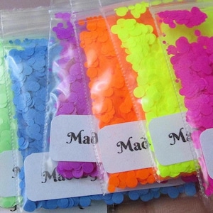 May include: A selection of brightly coloured confetti in clear plastic bags. The confetti is in neon shades of pink, orange, green, blue, and yellow. Each bag has a white label with the text "Made2GlitterCookie".