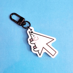May include: A white computer cursor-shaped keyring featuring a cartoon character with a pink nose and ears, outlined in dark brown. The charm is attached to a black metal lobster clasp, providing a functional way to secure keys or accessories.
