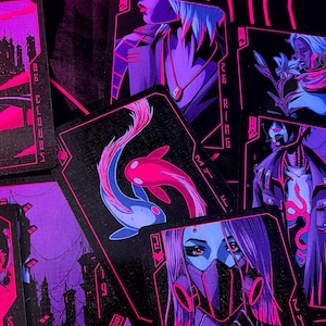 K&ouml;nnte beinhalten: Ein Kartenspiel mit einem futuristischen, Cyberpunk-Thema. Jede Karte zeigt einzigartige Illustrationen in Lila-, Rosa- und Schwarzt&ouml;nen. Die Karten zeigen verschiedene Figuren und Symbole, mit einem Fokus auf Neon-&Auml;sthetik.