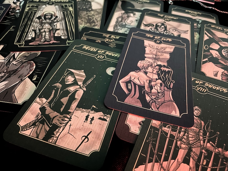 May include: A collection of tarot cards with black backgrounds and illustrations in shades of red and gold. The cards feature various figures and symbols, including a hooded figure with a sword, and a couple kissing. The cards are spread out on a dark surface.
