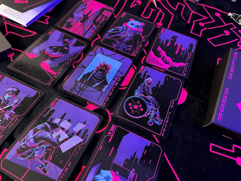 K&ouml;nnte beinhalten: Ein Kartenspiel mit futuristischem, Cyberpunk-Thema. Jede Karte zeigt eine einzigartige Illustration in Schwarz-, Lila- und Rosat&ouml;nen. Die Karten sind auf einer schwarzen Oberfl&auml;che mit passendem Design angeordnet, neben einer Box mit der Aufschrift "NEON MOON".