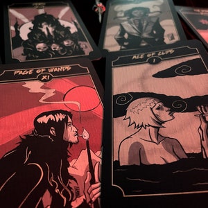 May include: A collection of tarot cards with black borders and illustrations in shades of gray and red. The "Page of Wands" card shows a figure with a lit match. The "Ace of Cups" card depicts a person in water. Other cards are visible.