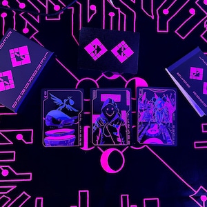 K&ouml;nnte beinhalten: Spielkarten mit neonrosa und schwarzen Grafiken. Die Karten zeigen Illustrationen eines Storchs, einer Kapuzenfigur und einer Gruppe von Personen. Die Kartenboxen und die Spieloberfl&auml;che haben passende geometrische Muster in Neonrosa.