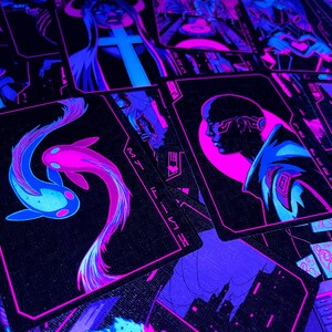 K&ouml;nnte beinhalten: Ein Kartenspiel mit futuristischer Neon-&Auml;sthetik. Die Karten zeigen Illustrationen in Blau-, Rosa- und Lilat&ouml;nen. Eine Karte zeigt zwei Koi-Fische, w&auml;hrend andere Figuren und Stadtlandschaften darstellen. Das Gesamtthema ist Cyberpunk.