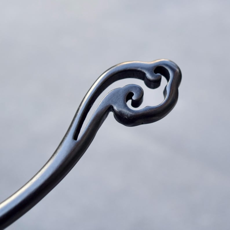 Pu&ograve; includere: Un fermacapelli in metallo grigio scuro con un design decorativo a forma di nuvola nella parte superiore. L'accessorio per capelli ha una forma curva e una finitura liscia e lucida, ideale per aggiungere un tocco di eleganza a qualsiasi acconciatura.