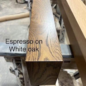 May include: Close-up of a rectangular wooden beam with an espresso finish on white oak. The wood grain is visible, showing a natural pattern. The text "Espresso on White oak" is printed on the wood.
