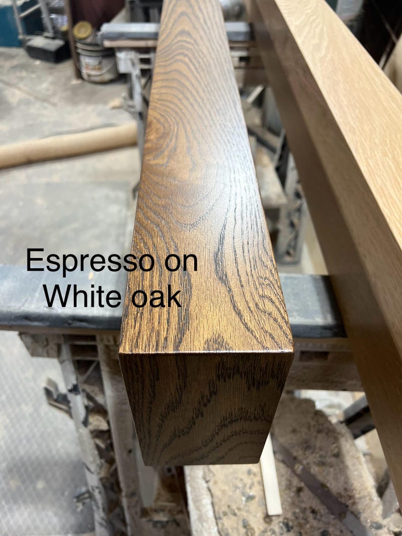 May include: Close-up of a rectangular wooden beam with an espresso finish on white oak. The wood grain is visible, showing a natural pattern. The text "Espresso on White oak" is printed on the wood.
