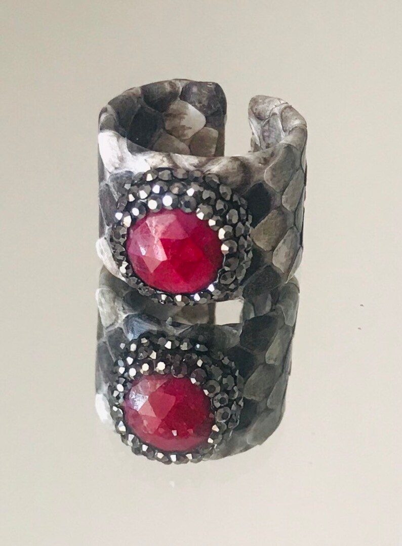 Faceted red garnet ring with druzys set in a grey shaded python adjustable band.