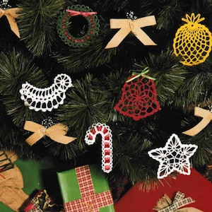Puede incluir: Un árbol de Navidad decorado con adornos de ganchillo, incluyendo un corazón, una estrella, una campana, un bastón de caramelo, una piña, una corona y un lazo. El árbol está rodeado de regalos envueltos.