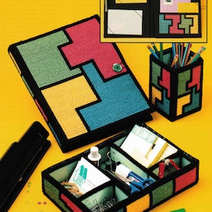 May include: A collection of handmade, colorful Tetris-themed office organizers. The set includes a binder, pencil holder, and a divided tray, all in vibrant hues of green, red, yellow, and blue, with black borders. The tray contains office supplies.