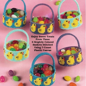 May include: Six brightly colored, stitched baskets filled with jelly beans. The baskets are decorated with yellow ducklings and have handles. The text reads "Enjoy Sweet Treats From These 6 Brightly Colored Baskets Stitched Using 7-Count Plastic Canvas."